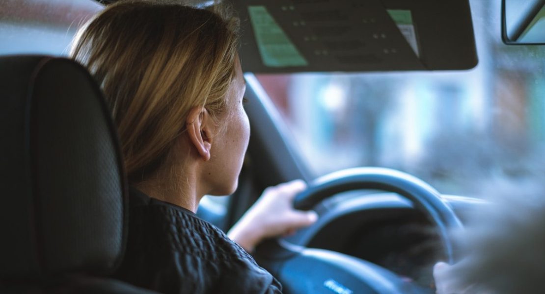 a woman sitting in a car with a steering wheel